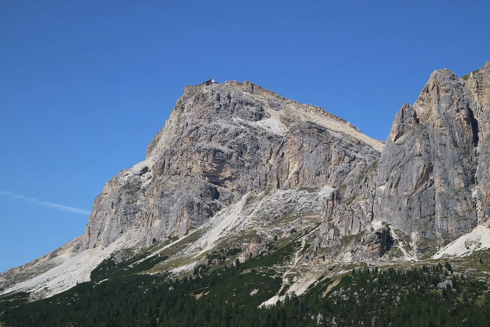 Le pareti rocciose del Piccolo Lagazuoi sotto un cielo azzurro, con boschi di conifere alla base